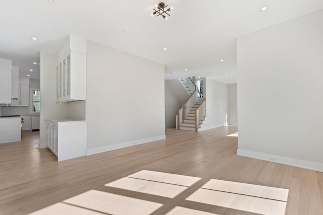 unfurnished living room featuring stairs, light wood-style flooring, and recessed lighting