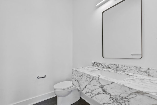 bathroom featuring a sink, baseboards, and toilet