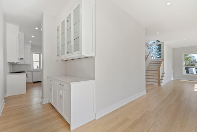 corridor featuring a wealth of natural light, recessed lighting, stairs, and light wood-type flooring