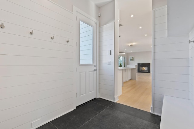 entryway with wooden walls and a lit fireplace