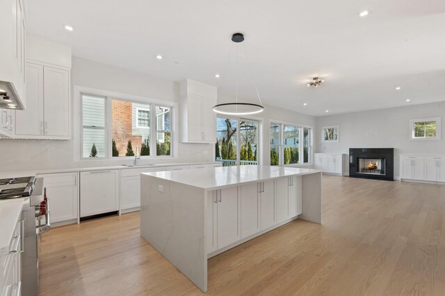 kitchen with white cabinets, plenty of natural light, light wood-style floors, and a kitchen island