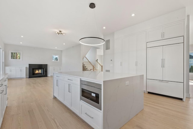 kitchen with built in appliances, white cabinetry, and light wood-type flooring