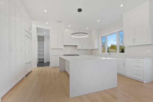 kitchen with white cabinetry, light wood-style floors, tasteful backsplash, and a kitchen island