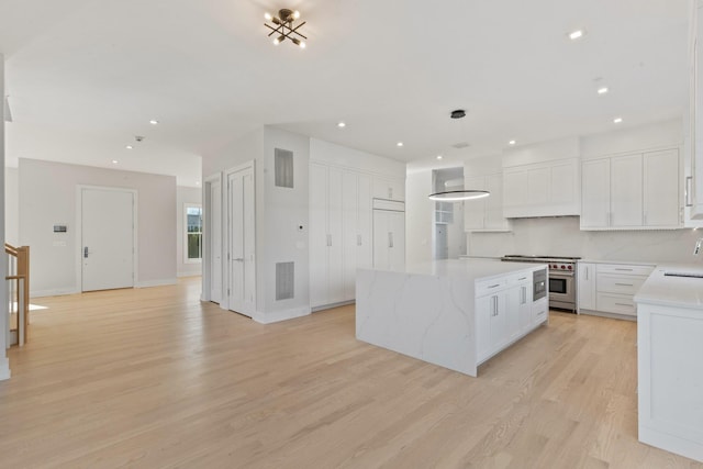 kitchen featuring tasteful backsplash, a center island, custom exhaust hood, white cabinets, and stainless steel range