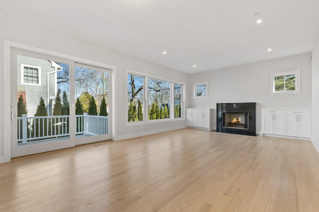 unfurnished living room featuring recessed lighting, plenty of natural light, and light wood-style floors