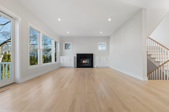 unfurnished living room featuring visible vents, baseboards, a healthy amount of sunlight, and light wood finished floors