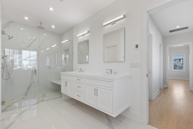 bathroom with a marble finish shower, visible vents, double vanity, recessed lighting, and a sink