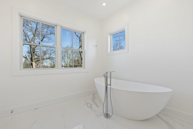 bathroom featuring baseboards, a soaking tub, and marble finish floor