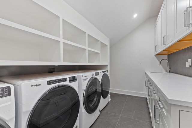 washroom with baseboards, cabinet space, a sink, washer and dryer, and dark tile patterned floors