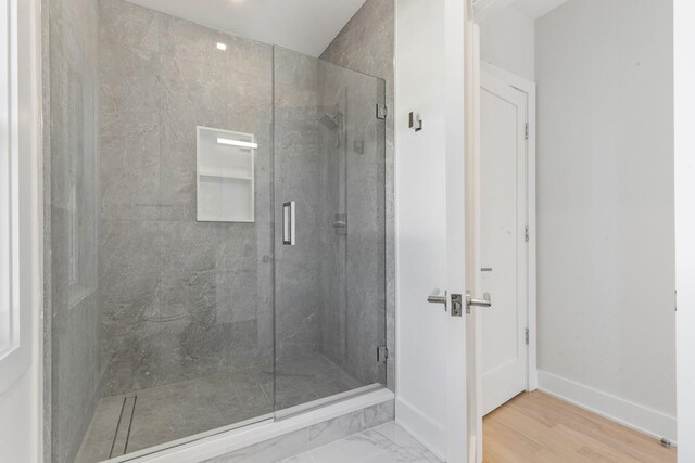 bathroom featuring a shower stall, marble finish floor, and baseboards