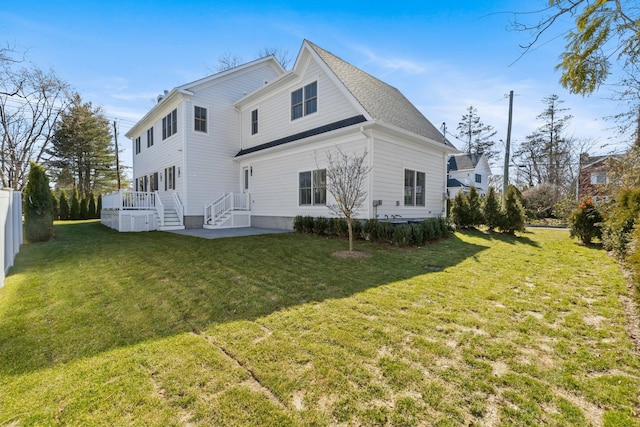 rear view of property featuring a lawn, roof with shingles, and fence