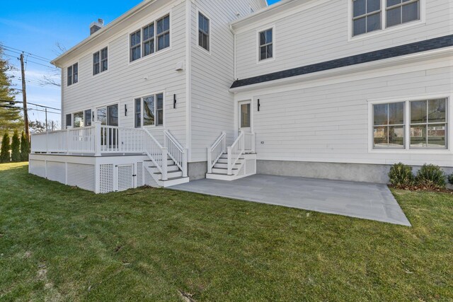 rear view of house with a wooden deck, a lawn, a chimney, and a patio