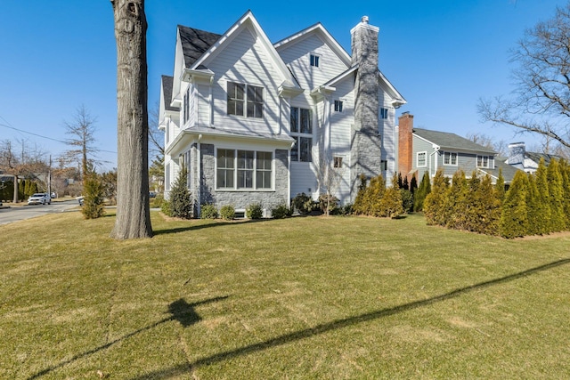 view of front of home with stone siding, a chimney, and a front lawn