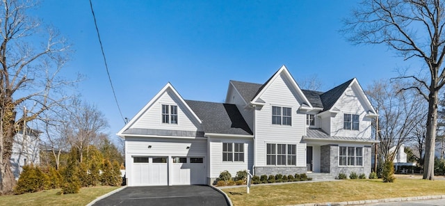 view of front of house featuring stone siding, a garage, driveway, and a front lawn