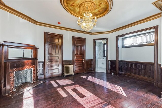 interior space featuring dark hardwood / wood-style floors, radiator heating unit, crown molding, and an inviting chandelier