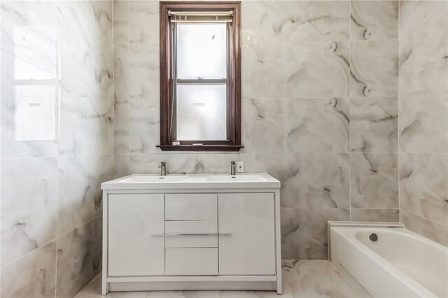 bathroom featuring vanity, a tub to relax in, and tile walls