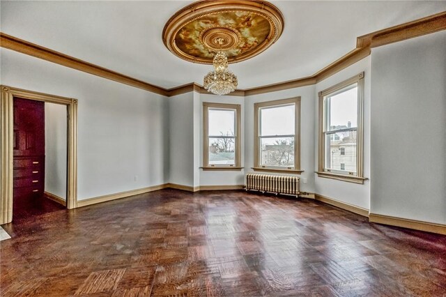 spare room with a wealth of natural light, ornamental molding, radiator, and a notable chandelier