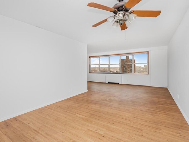 unfurnished living room with ceiling fan, radiator heating unit, and light hardwood / wood-style flooring