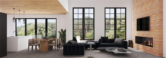 sunroom / solarium featuring a healthy amount of sunlight, a large fireplace, and wooden ceiling