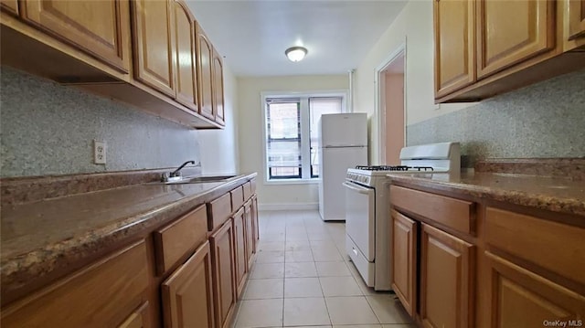 kitchen featuring backsplash, sink, light tile patterned floors, and white appliances