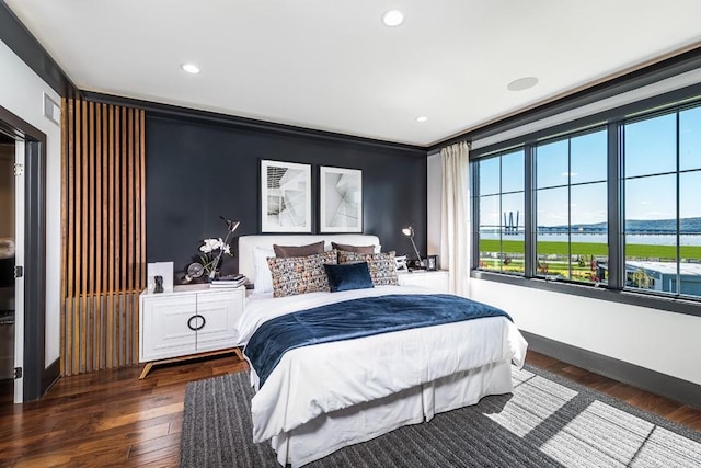 bedroom with crown molding, a water view, and dark hardwood / wood-style floors