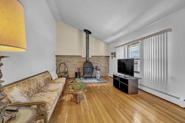 138 Reinhardt Rd, Middletown, NY 10940 - living room featuring vaulted ceiling, a wood stove, wood finished floors, a baseboard radiator, and a wainscoted wall