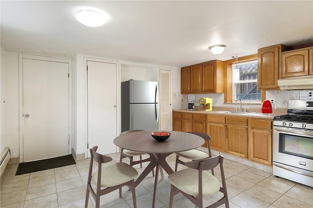 kitchen featuring stainless steel refrigerator, gas range, sink, backsplash, and light tile patterned floors