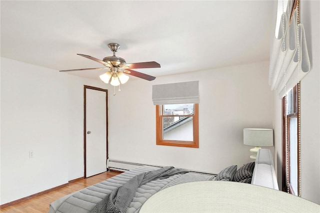 bedroom with ceiling fan, baseboard heating, and light hardwood / wood-style flooring