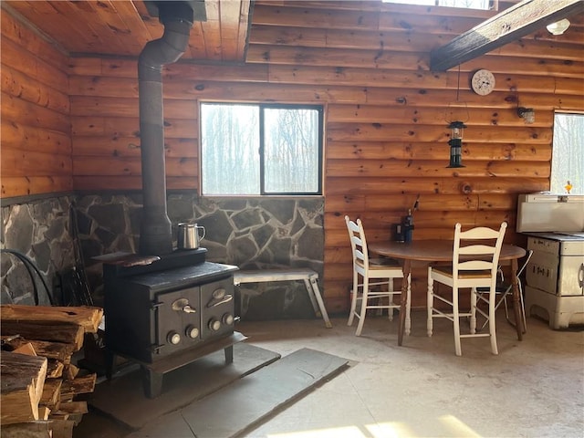 dining area with a wood stove and rustic walls