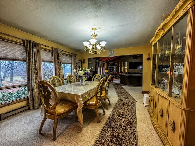 dining area featuring a baseboard heating unit, a textured ceiling, a wealth of natural light, and an inviting chandelier