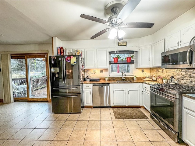 kitchen featuring stainless steel appliances, ceiling fan, sink, white cabinets, and light tile patterned flooring