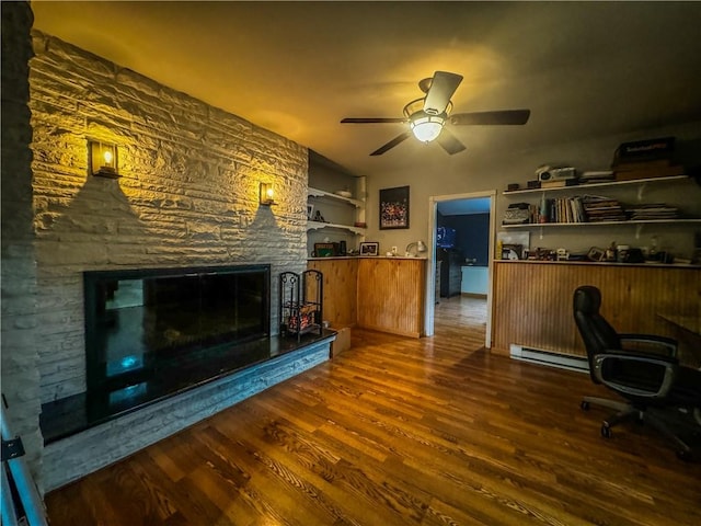 unfurnished office featuring hardwood / wood-style flooring, a stone fireplace, and ceiling fan