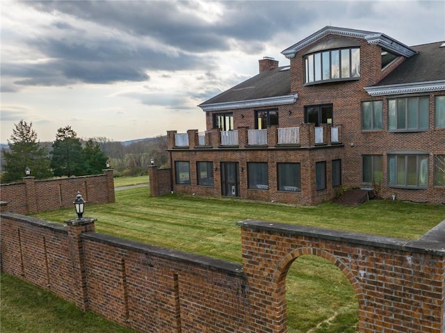 back of property with a lawn and a balcony