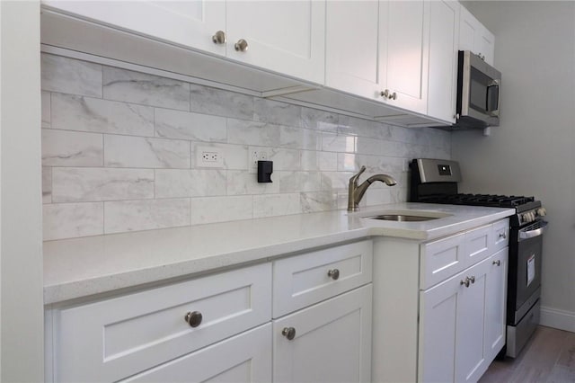 5645 Netherland Ave Unit 6A, Bronx, NY 10471 - kitchen with stainless steel appliances, a sink, tasteful backsplash, white cabinets, and wood finished floors