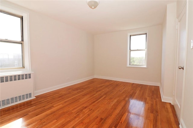 empty room with radiator heating unit and hardwood / wood-style flooring