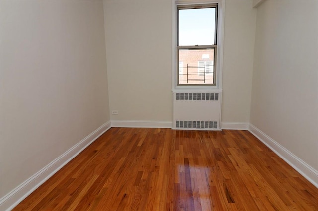 empty room with light wood-type flooring and radiator