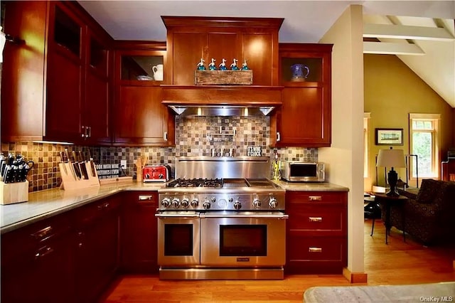 kitchen with vaulted ceiling, tasteful backsplash, light hardwood / wood-style floors, and range with two ovens