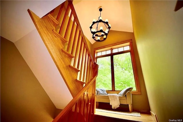 staircase featuring hardwood / wood-style floors, an inviting chandelier, and lofted ceiling