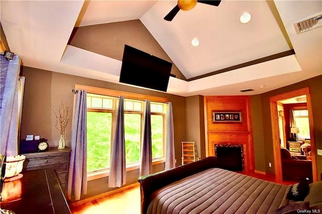 bedroom with ceiling fan, a large fireplace, vaulted ceiling, and hardwood / wood-style flooring