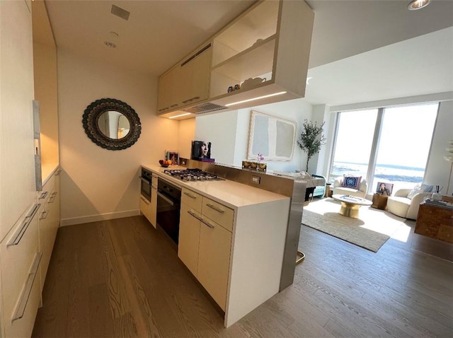 kitchen featuring hardwood / wood-style flooring, oven, kitchen peninsula, and stainless steel gas cooktop