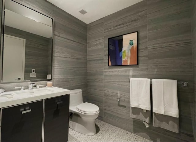 bathroom featuring tile patterned floors, vanity, toilet, and tile walls