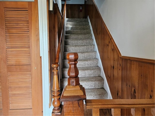 stairs featuring hardwood / wood-style floors and wood walls