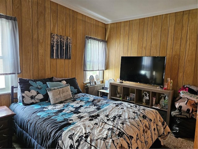 bedroom featuring ornamental molding, multiple windows, and wooden walls