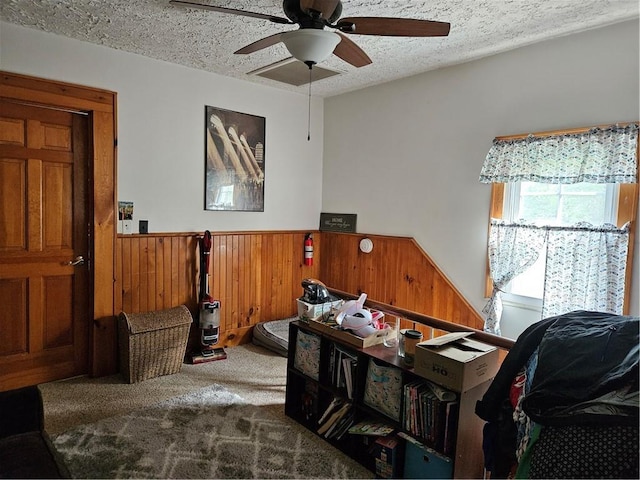 interior space featuring ceiling fan, wood walls, and a textured ceiling