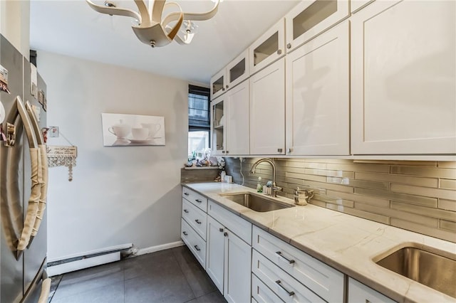 kitchen with light stone countertops, a baseboard heating unit, sink, white cabinetry, and stainless steel refrigerator