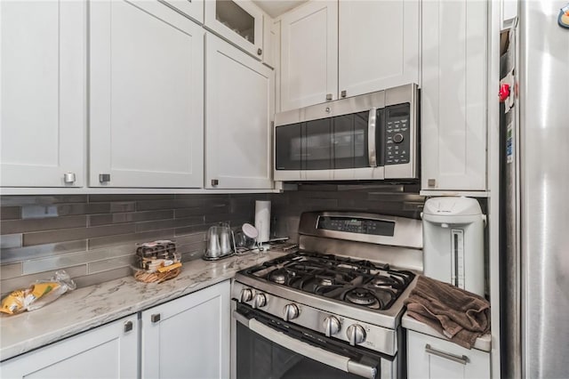 kitchen with stainless steel appliances, white cabinetry, and tasteful backsplash