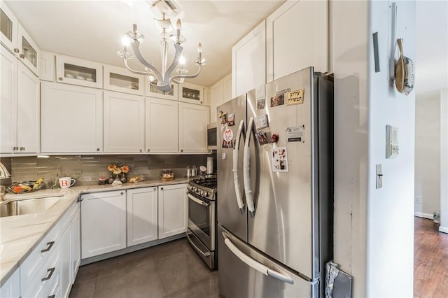 kitchen with white cabinetry, sink, light stone counters, decorative backsplash, and appliances with stainless steel finishes