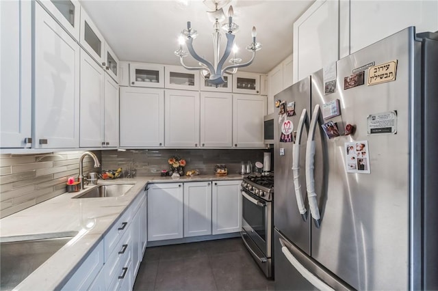 kitchen with light stone countertops, decorative backsplash, stainless steel appliances, sink, and white cabinetry