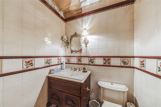 bathroom with vanity, toilet, and tile walls