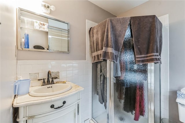 bathroom with vanity, an enclosed shower, and tile walls